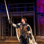 Allie Pratt crouching on one knee, holding up a sword
